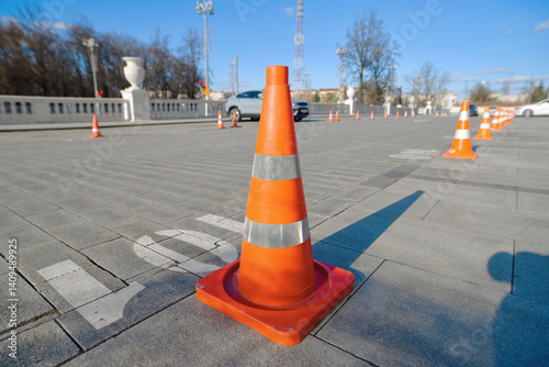 Obraz na płótnie Row of bright orange traffic cones neatly aligned to reserve parking spots in public area. Traffic cones standing in an orderly line to mark and protect reserved parking spaces. w salonie