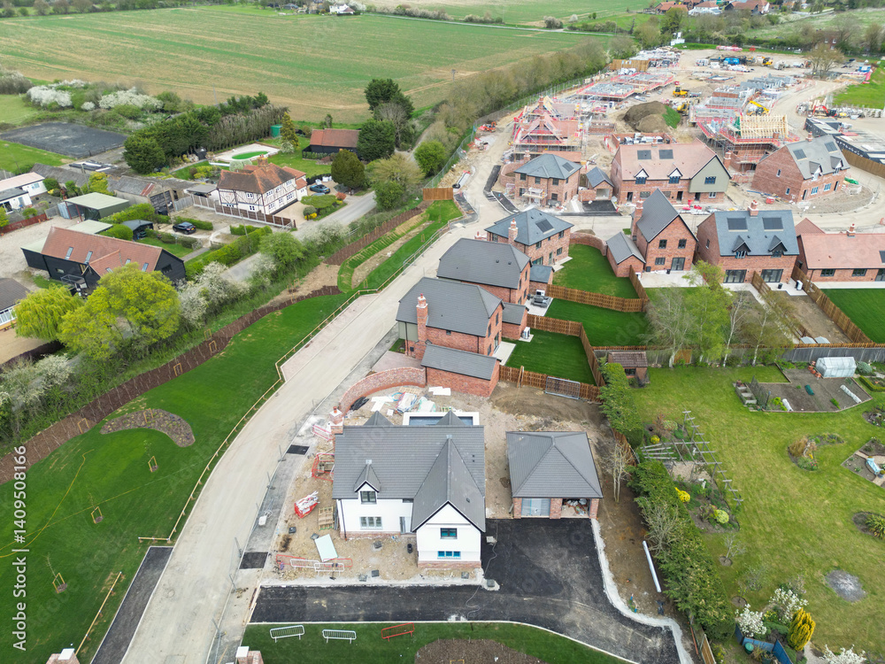 Aerial view of a large White House located at the entrance to a rural housing development project in the east of England. Part of an expansion of this rural village.