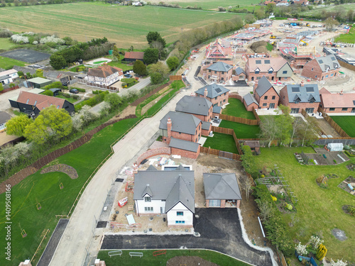 Obraz na płótnie Aerial view of a large White House located at the entrance to a rural housing development project in the east of England. Part of an expansion of this rural village. w salonie