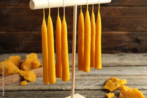 Fotografia Hand dipped beeswax candles drying on rack on wooden table
