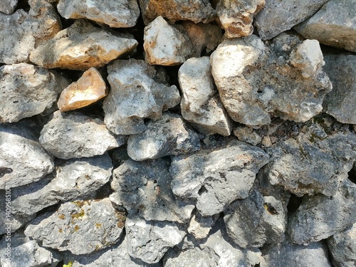 Close-up of a rough stone wall with natural textures and earthy tones. Ideal for backgrounds, construction themes, nature textures, or rustic design elements