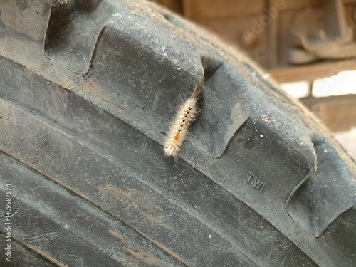 Close-up of a worn, textured tire with a visible puncture or damage. Industrial or automotive concept