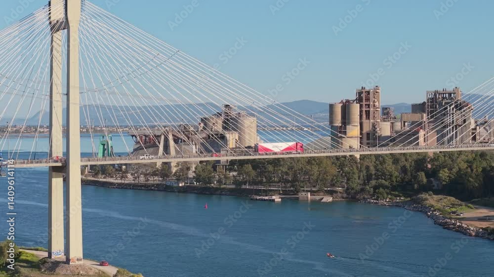 Aerial shot shows vehicles crossing the Chalkida High Bridge as the abandoned cement factory stands in the background. A unique mix of motion, industry, and urban contrast