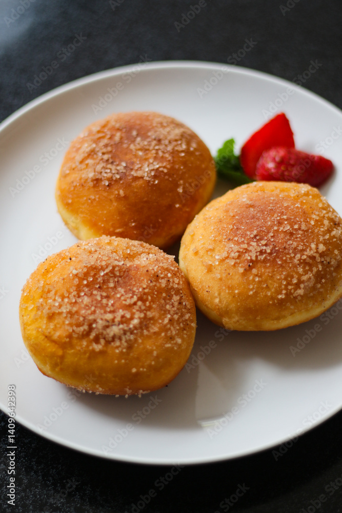 A handmade bombolone or bomboloni is an Italian-filled doughnut that is eaten as a snack or dessert. Selective focus. A handmade bombolone or bomboloni is an Italian-filled doughnut that is eaten as a snack or dessert. Selective focus.