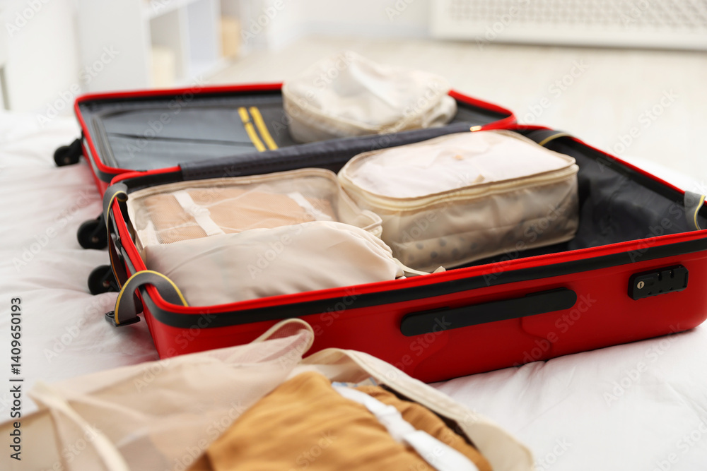 Packing cubes in suitcase on bed indoors, closeup