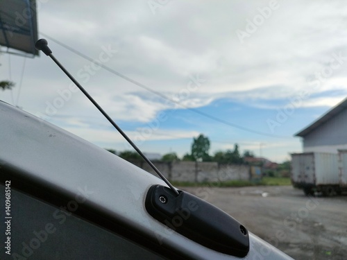 Close-up of a car radio antenna mounted on a vehicle with a blurred outdoor background. Ideal for automotive, communication, transportation, and technology themes