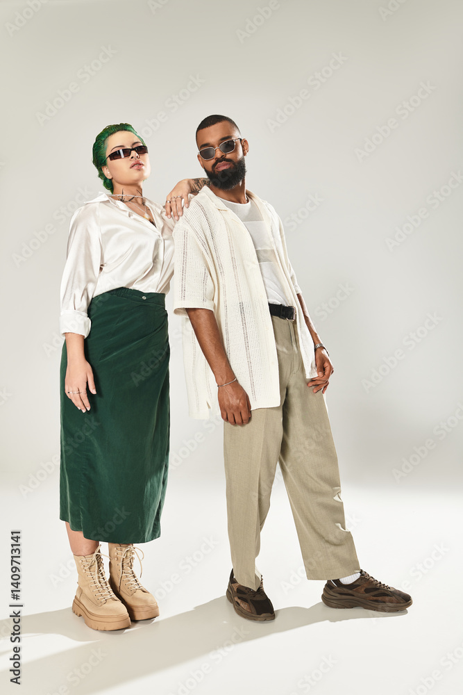 Stylish multicultural couple showcasing trendy looks in a modern studio setting