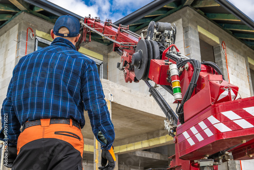 Construction Worker Operates Crane at Building Site in Daytime