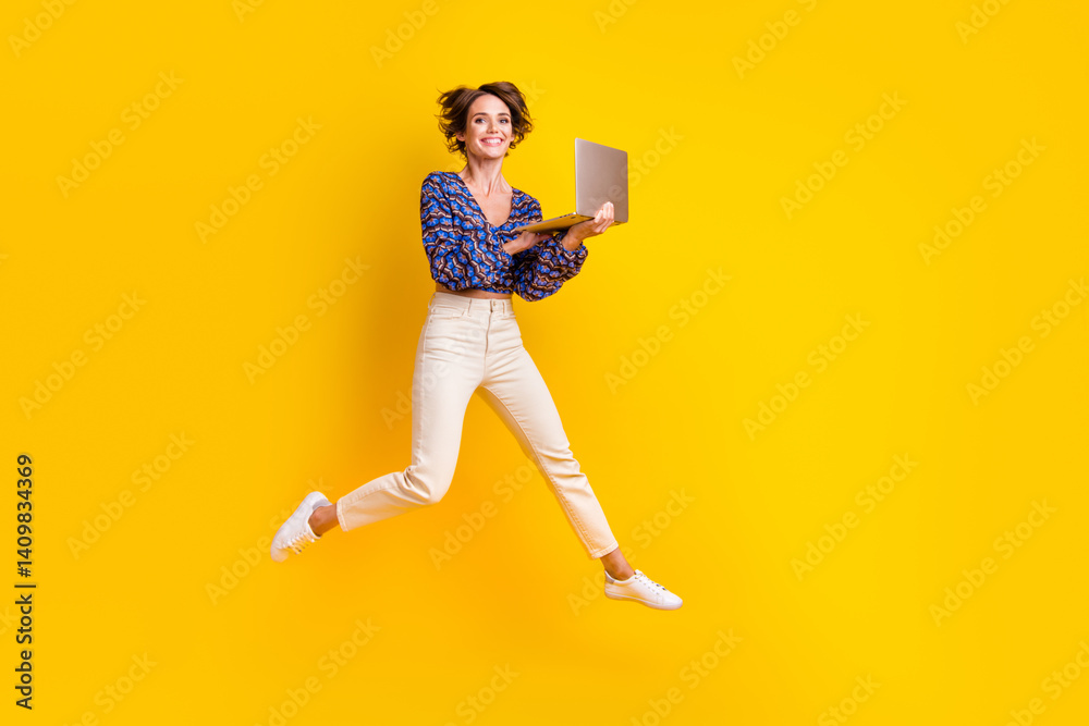 Full body length photo of happy apple macbook pro enjoyer girl loves her new computer jumping air isolated on yellow color background
