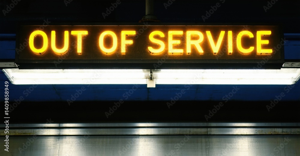 Fototapeta premium Neon out of service sign glowing in dull yellow above subway entrance deep navy and bright silver symbolizing restricted access