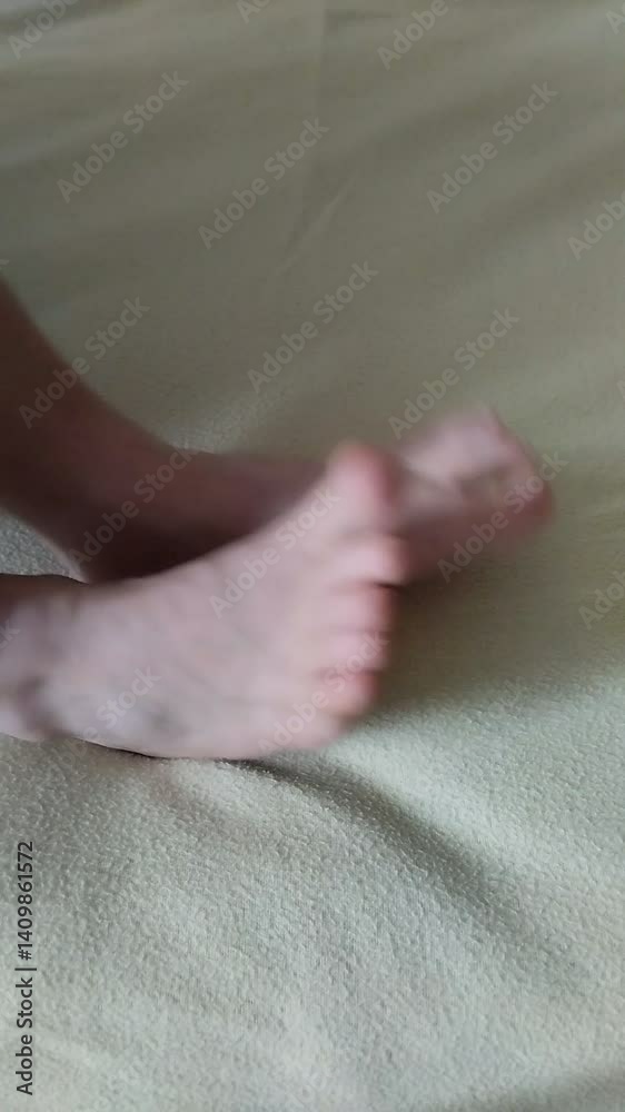 Un primer plano de una de mujer moviendo sus pies en una cama. Video vertical