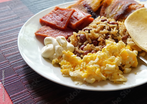 Traditional Costa Rican breakfast, rice and beans, called Gallo Pinto with eggs, tortilla, sausage and plantain.