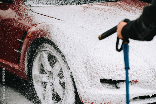 Foamy red sports car getting pressure washed photo