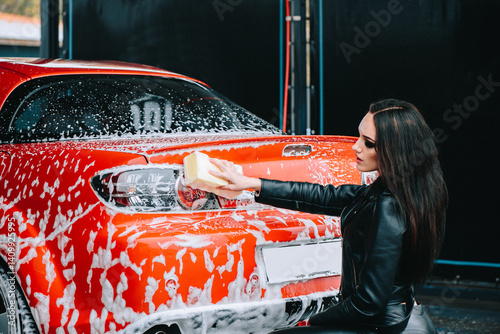 Woman washing sporty red car at urban car wash