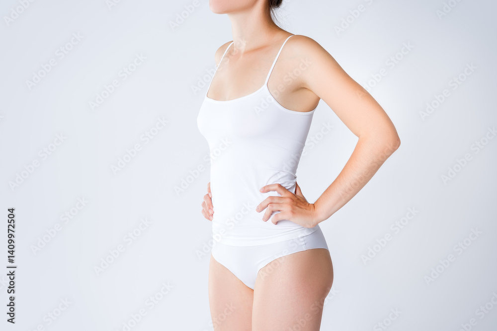 Fototapeta premium Slim woman in white underwear on gray background, body care concept