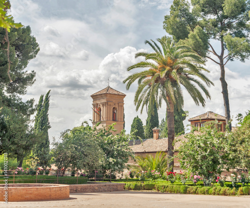 Alhambra, Granada, Spain: Andalusian architecture amidst lush gardens under a cloudy sky