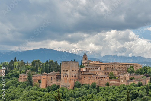 Alhambra palace complex nestled among trees with Sierra Nevada mountains behind, Granada, Spain