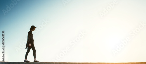 young girl in black clothes and a hat stands against the blue sky. philosophical symbolic path to future. Long horizontal banner template empty copy space. Free spirit concept. sad thoughtful emotions