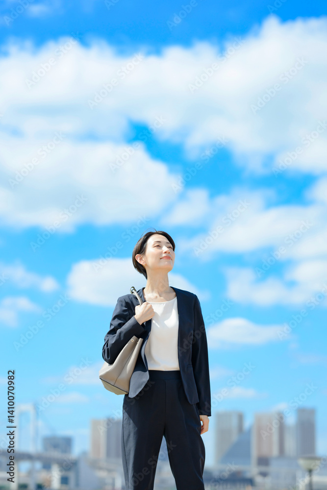 青空をバックに立つビジネスウーマン