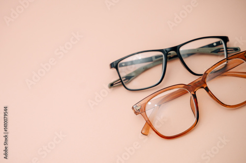 Eyeglasses for nearsightedness or farsightedness placed on a peach background, concept of vision correction, eye care, and optical accessories.