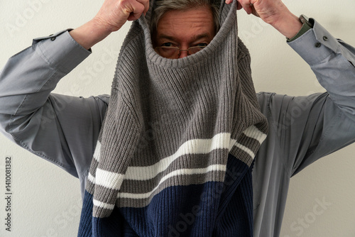 Male is putting on or off sweater. White background. Horizontal shot.