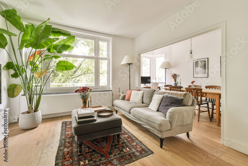 Konstfotografi A stylish modern living room with abundant natural light, featuring a sofa, decorative plants, and a cozy atmosphere that feels warm and welcoming