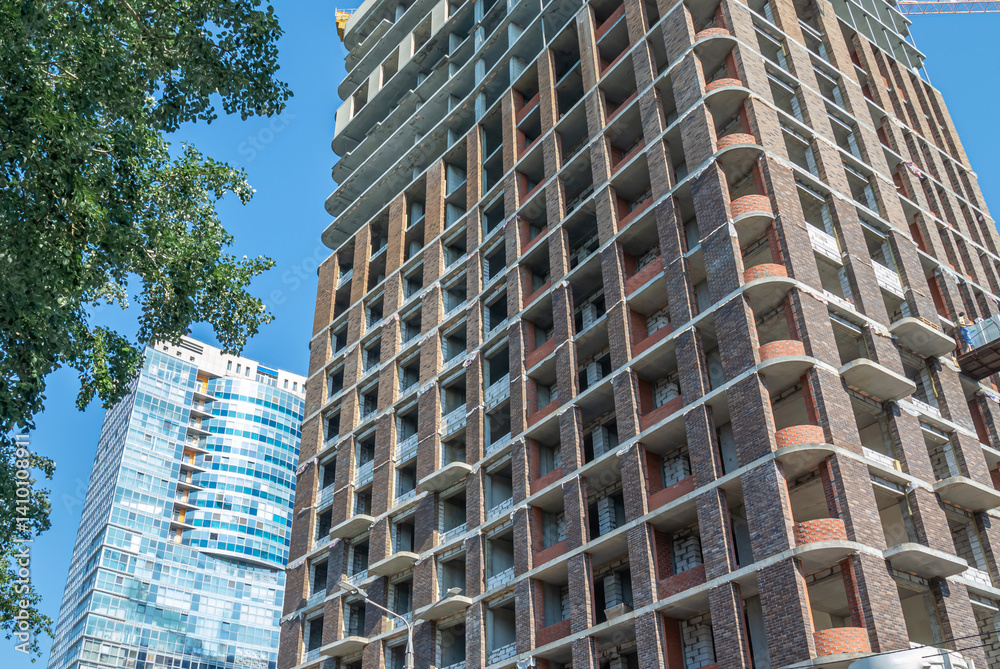 Fototapeta premium The exterior walls of the high-rise building are lined with decorative facade bricks. Technologies for the construction of high-rise buildings. The building's frame is made of reinforced concrete.