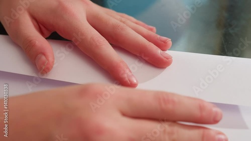 Wallpaper Mural Close-up of hand folding paper carefully, straightening edges on glass table to create paper craft, focusing on precision and neatness Torontodigital.ca