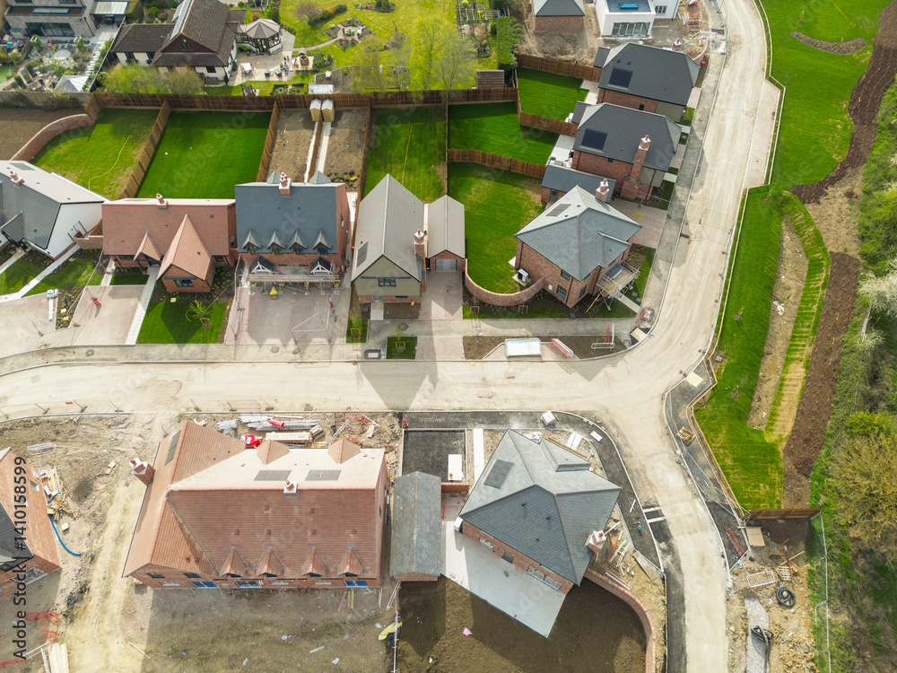 Drone survey of new house builds on a housing development site in rural Britain. Both affordable and more expensive detached family homes can be seen near completion.