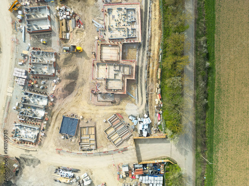 Obraz na płótnie Drone high altitude view of new foundations and house footings seen on a housing development site in rural England. Seen adjacent to a farm field. w salonie