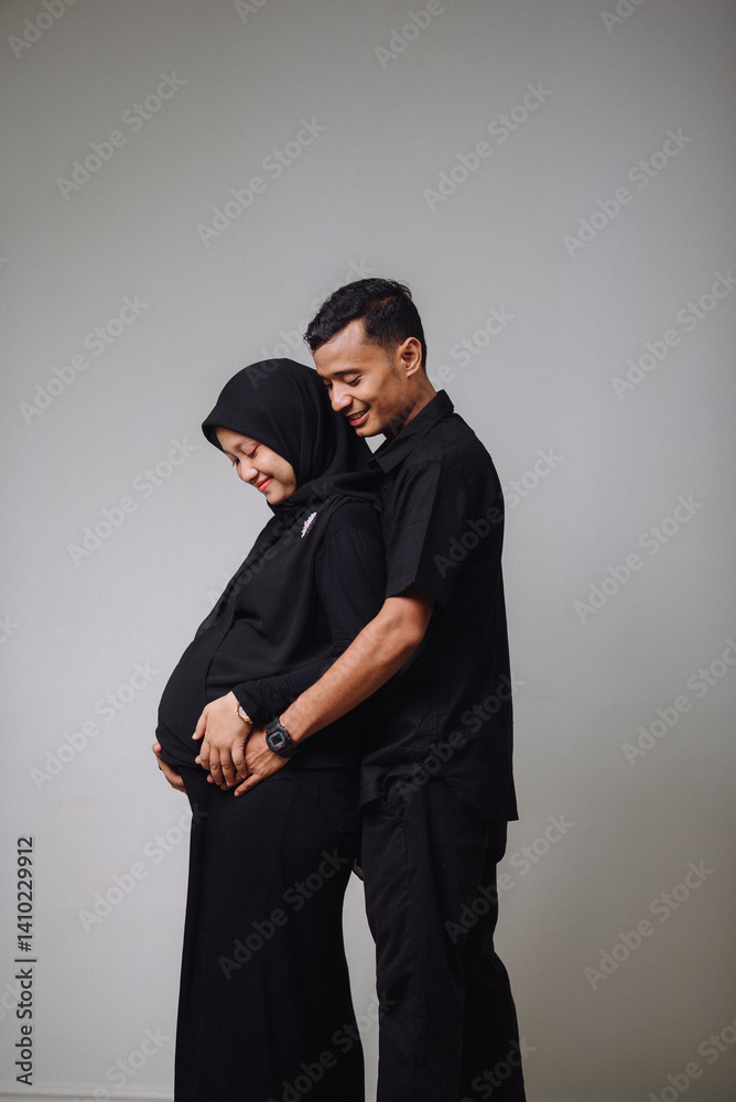Black and white maternity portrait of a Muslim couple. The pregnant woman wears elegant black attire, standing beside her husband in a black shirt and pants. Emotional, modern, and timeless. Black and white maternity portrait of a Muslim couple. The pregnant woman wears elegant black attire, standing beside her husband in a black shirt and pants. Emotional, modern, and timeless.