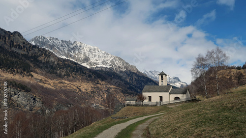 Catholic church in the Swiss Alps with mountains in the background in early spring