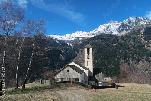 Catholic church in the Swiss Alps with mountains in the background in early spring