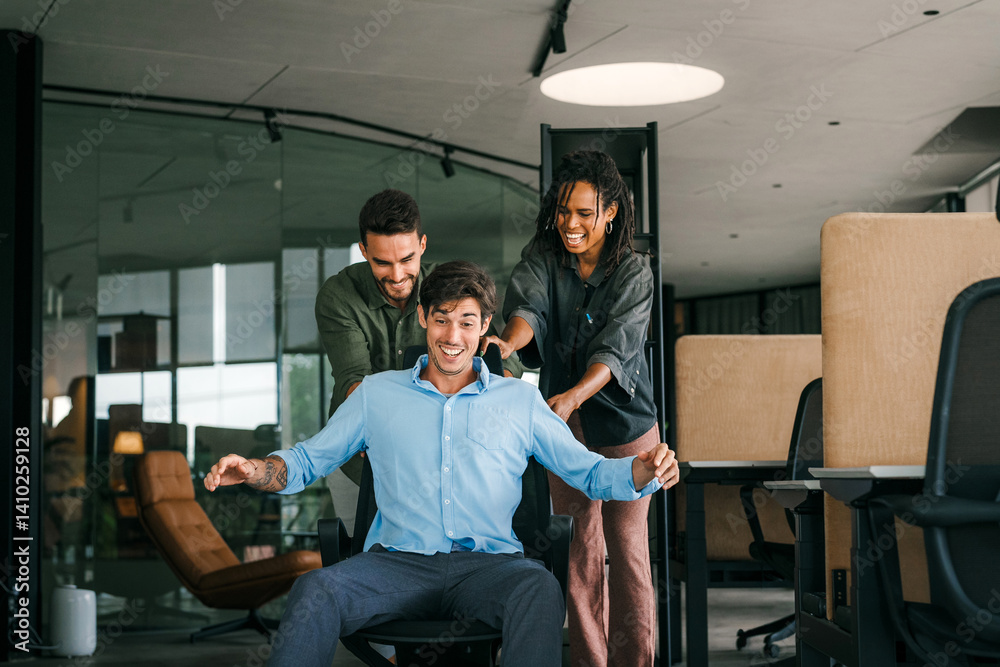 Naklejka premium Young colleagues group having fun together riding on chairs in office diverse excited office workers