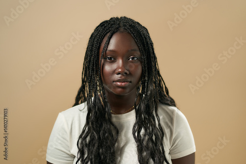 Young black woman posing with long braided hair on beige background