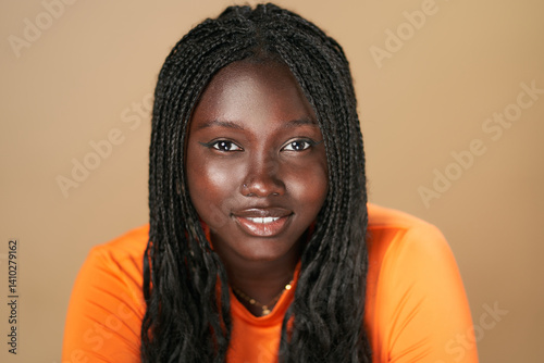 Young black woman with braids smiling in orange shirt