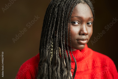 Young black woman posing with long braided hair and red sweater