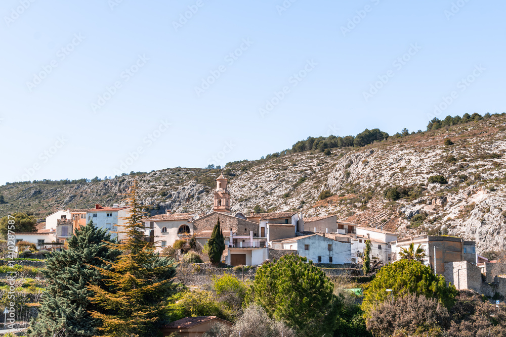 a small village on a hillside with trees and a church.La vall de gallinera, Alicante, Spain