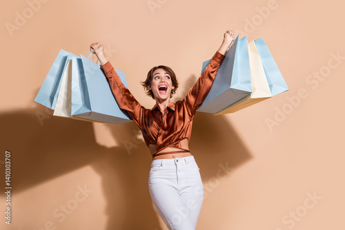 Photo of sweet impressed lady dressed brown top rising shoppers looking empty space isolated beige color background