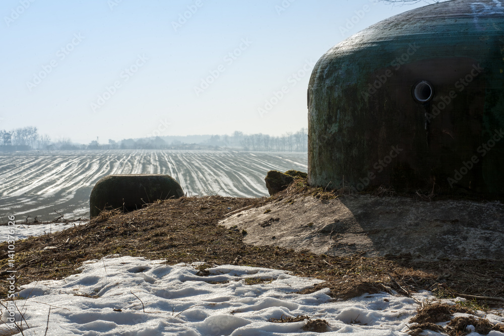 Obraz premium Dwie stalowe kopuły poniemieckich bunkrów wśród zaśnieżonych pól
