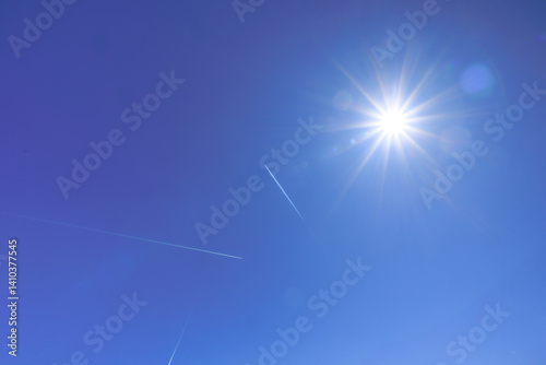 Sunny blue sky with contrails from passing aircraft..