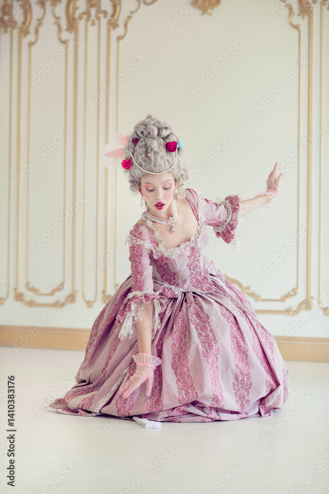 Fototapeta premium Elegantly dressed woman in ornate pink gown reminiscent of historical royalty, gracefully poses within a beautifully decorated interior