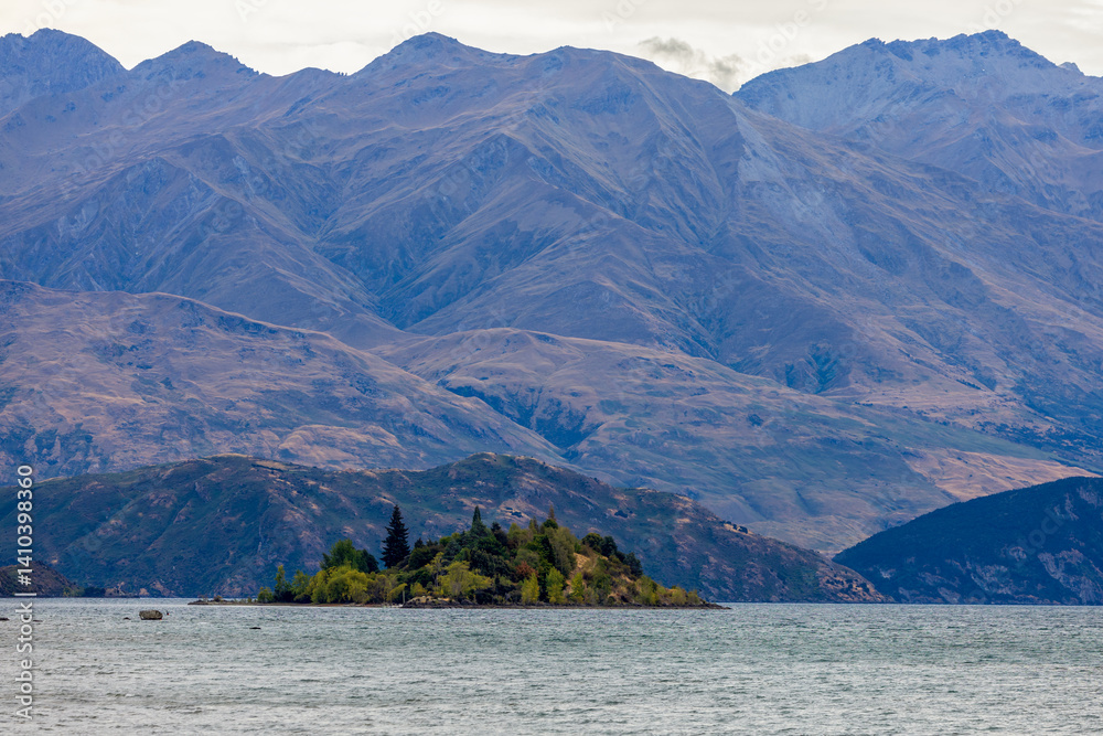 Lake Wanaka, a summer cloudy afternoon with a mountain range and the town of Wanaka on the shore. South Island, New Zealand