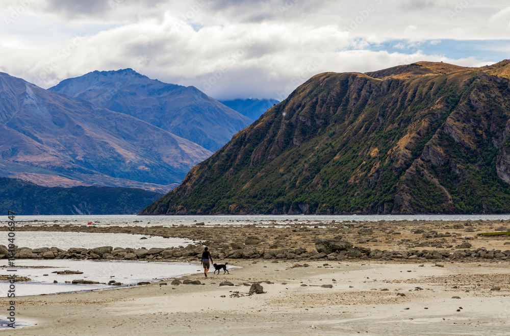 Lake Wanaka, a summer cloudy afternoon with a mountain range and the town of Wanaka on the shore. South Island, New Zealand