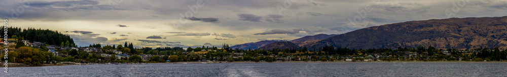 Lake Wanaka, a summer cloudy afternoon with a mountain range and the town of Wanaka on the shore. South Island, New Zealand