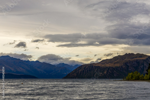 Obraz na płótnie Lake Wanaka, a summer cloudy afternoon with a mountain range and the town of Wanaka on the shore. South Island, New Zealand w salonie