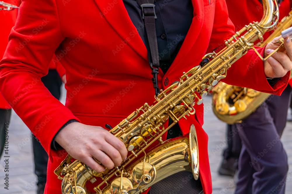 Naklejka premium musician in a red suit plays the saxophone during a street performance. Other musicians in similar outfits are visible in the background