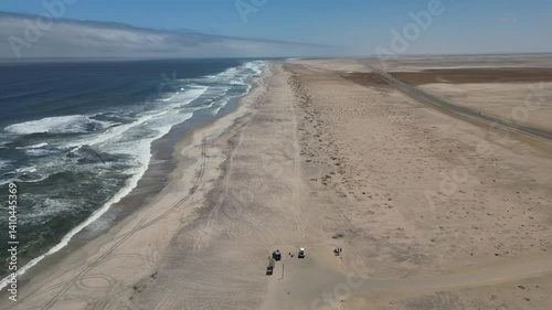Drone flying over Skeleton Coast with ocean waves on a sunny day with blue sky