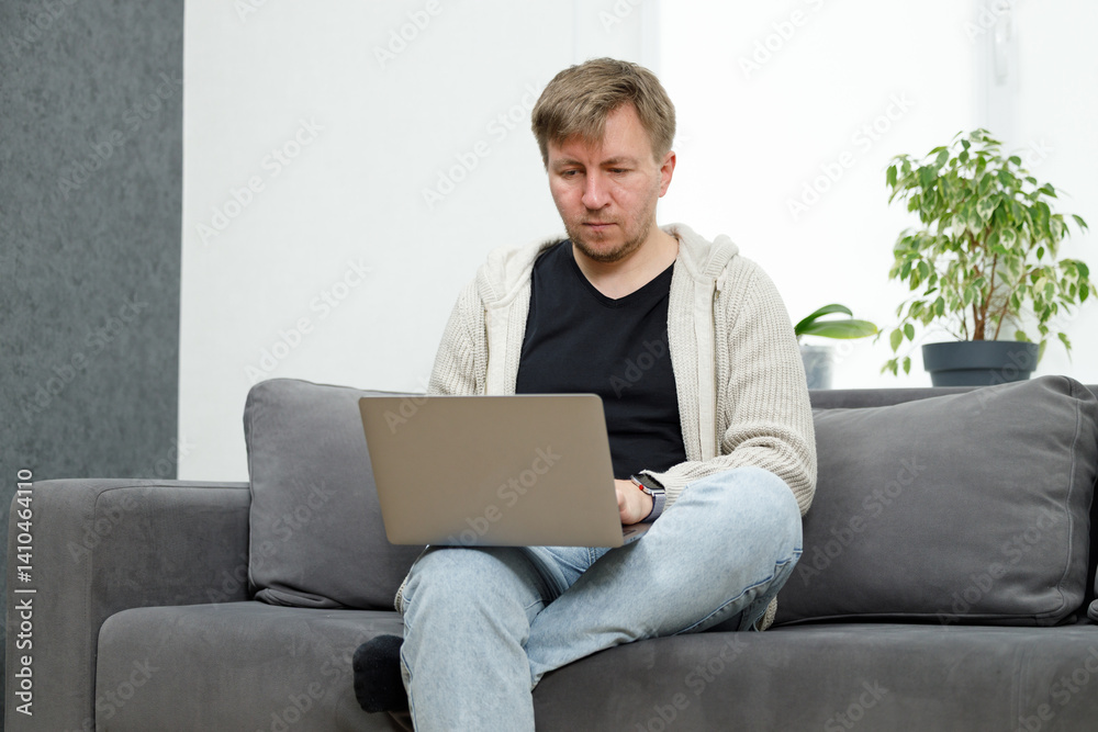 Man on sofa in living room working on laptop Man on sofa in living room working on laptop