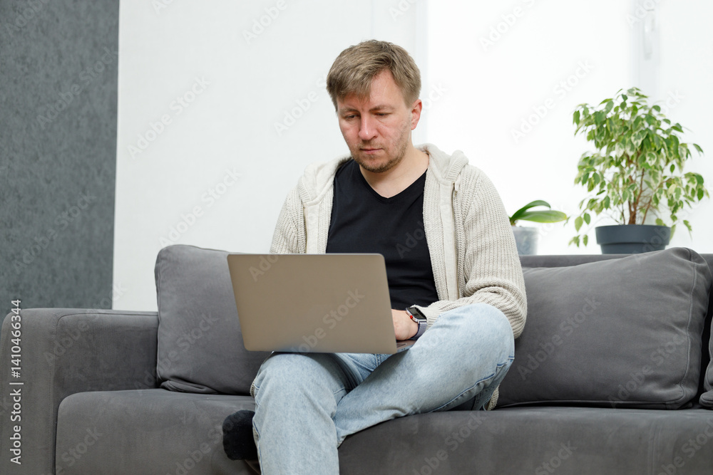 Man on sofa in living room working on laptop